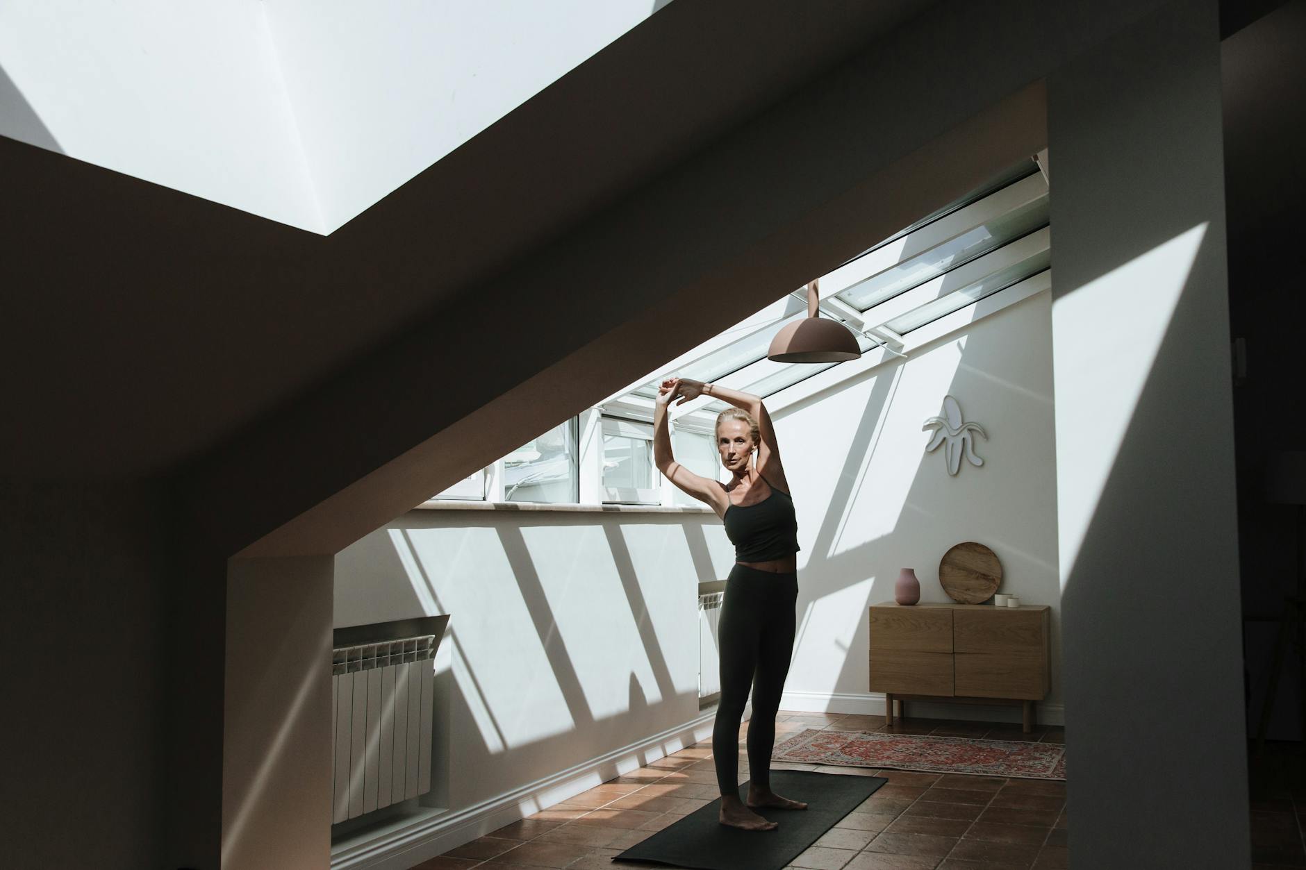 Person stretching peacefully in a bright, sunlit room, embodying well-being.